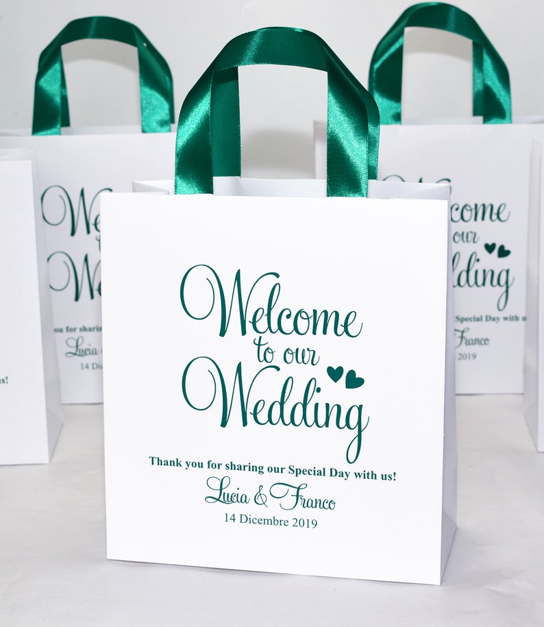 May include: White gift bag with green satin handles and the text "Welcome to our Wedding" in green cursive font. The bag also includes the names Lucia & Franco and the date 14 Dicembre 2019.