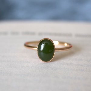 May include: A gold ring with a dark green oval gemstone.