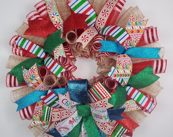 May include: A festive Christmas wreath with a circular design. It features red, green, and blue ribbons, along with candy cane and peppermint patterns. The wreath includes the text "Christmas Me".