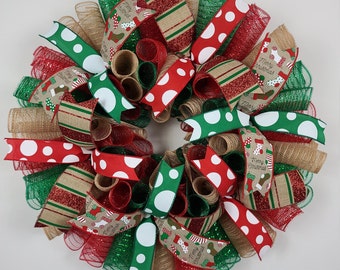 May include: A Christmas wreath with red, green, and brown burlap ribbon. The ribbon has white polka dots and a "Merry Christmas" print with stockings.