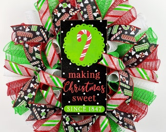 May include: A Christmas wreath with red, green, and white ribbon and a sign that says "making Christmas sweet since 1847".
