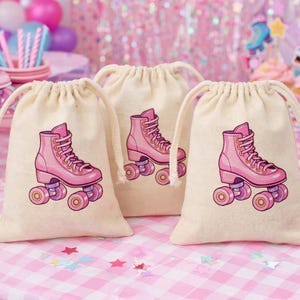 Könnte beinhalten: Drei beigefarbene Kordelzugbeutel mit einem rosa Rollschuh-Design. Die Rollschuhe haben lila Rollen. Die Beutel befinden sich auf einer rosa-weiß karierten Tischdecke mit Partydekorationen im Hintergrund.