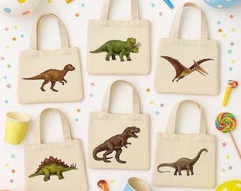 Puede incluir: Una colección de bolsas de mano de lona beige, cada una con una ilustración diferente de dinosaurio en tonos marrones y verdes. Los dinosaurios incluyen un T-Rex, un Estegosaurio y un Pterodáctilo. Las bolsas están dispuestas sobre una superficie blanca con decoraciones de fiesta coloridas.