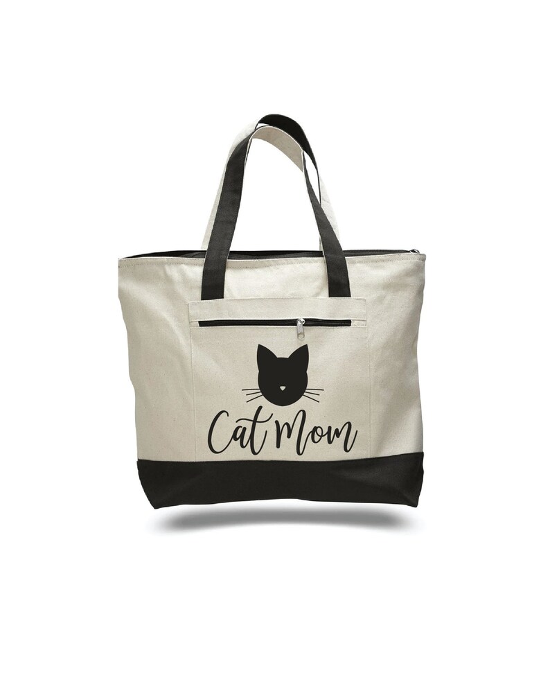 May include: A white canvas tote bag with black handles and a black bottom. The bag has a black cat silhouette and the text "Cat Mom" printed on the front.