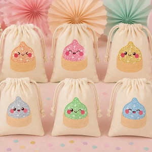 May include: Six off-white drawstring pouches made of fabric, each featuring a glittery, cartoon-style dumpling character with a unique color and facial expression. The dumplings are colored orange, pink, yellow, silver, green, and blue.