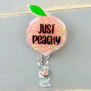 May include: Peach-shaped badge holder with glitter and the text "Just Peachy".