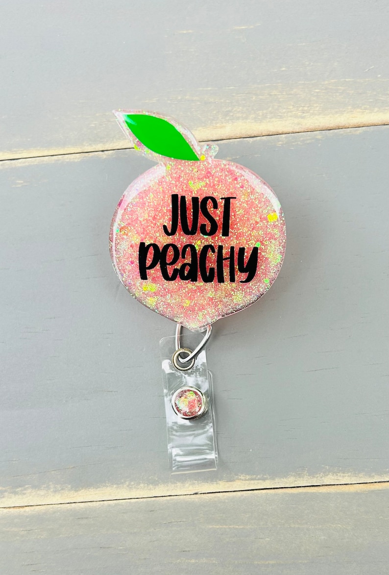 May include: Peach-shaped badge holder with glitter and the text "Just Peachy".