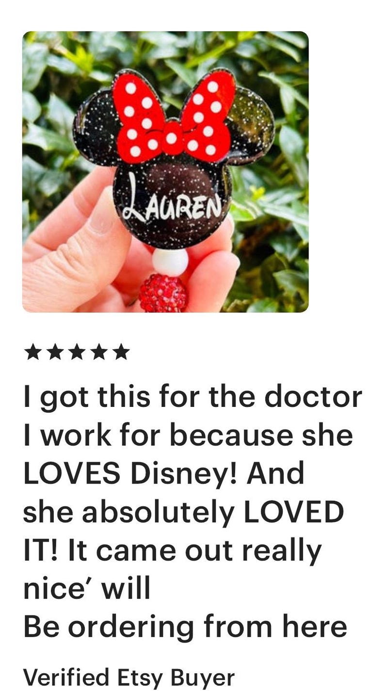 May include: A black and red Minnie Mouse-themed name tag with glitter and white polka dots. The name "Lauren" is written in white on the tag.