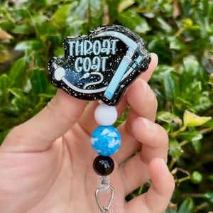 May include: A black and glittery badge reel with the text "THROAT COAT" and a medical instrument design in blue and white. The badge reel has a beaded accent in white, blue, and black.