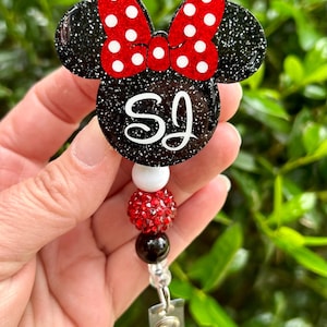 May include: Black and red glitter Minnie Mouse themed badge holder with the initials "SJ" and a red rhinestone charm.