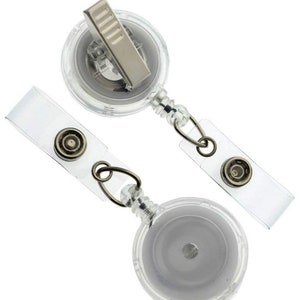May include: Two clear retractable badge reels with a silver clip and a clear plastic strap. The reels are designed to hold a badge or ID card.