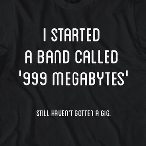 Peut inclure: T-shirt noir avec un texte blanc qui dit "J'ai monté un groupe appelé '999 mégaoctets' Je n'ai toujours pas eu de concert."