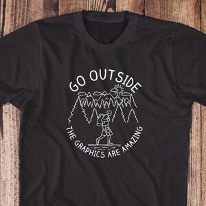 May include: Black t-shirt with a white graphic design of a person hiking in a forest with the text "GO OUTSIDE THE GRAPHICS ARE AMAZING".
