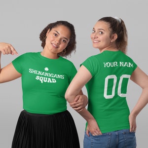 Puede incluir: Dos camisetas verdes con texto blanco. Una camiseta dice "Shenanigans Squad" con un tr&eacute;bol. La otra camiseta dice "Your Name" y tiene un n&uacute;mero blanco "00" en la espalda.