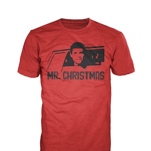 May include: Red t-shirt with a black and white image of a man in a car with the text "MR. CHRISTMAS" printed on the front.