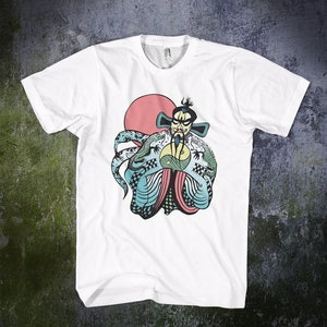 May include: A white short-sleeve t-shirt featuring a graphic illustration of a stylized figure with a beard and traditional headwear, wearing a robe with dragon motifs and a yin-yang symbol, set against a large solid red circle.