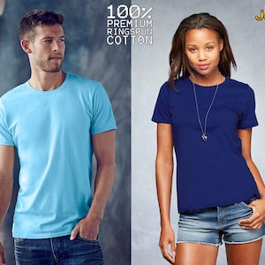 May include: A light blue crew neck t-shirt and a dark blue crew neck t-shirt. The text 100% PREMIUM RINGSPUN COTTON and the logo shirt Jerks are visible at the top. Both shirts feature short sleeves and a solid color design.