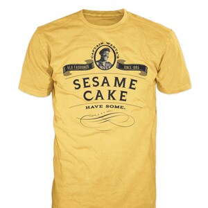 May include: Yellow t-shirt with a black and white graphic of a logo that says "Captain Wanta's Old Fashioned Sesame Cake Have Some. Since 1995."