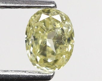 May include: A pale yellow oval-shaped diamond gemstone held in tweezers.