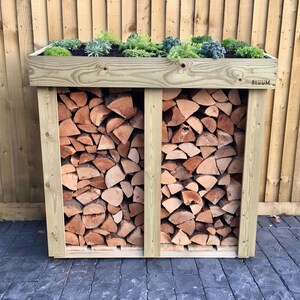 May include: A wooden log storage rack with a green plant growing on top. The rack is divided into two sections and has a label that says "BLOOM".