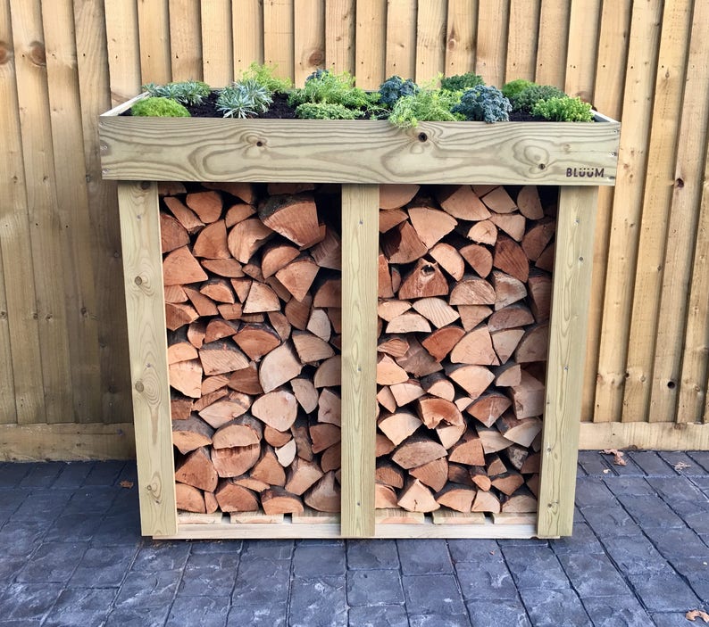 May include: A wooden log storage rack with a green plant growing on top. The rack is divided into two sections and has a label that says "BLOOM".