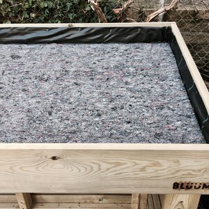 May include: A wooden raised garden bed with a black liner and a gray fabric lining. The bed is labeled "BLOOM" on the front.