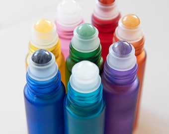 May include: Eight glass roller bottles with different colored glass and stone roller balls. The colors are blue, green, purple, red, yellow, orange, white, and clear.