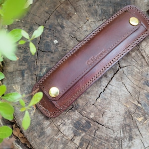 May include: A brown leather wrist strap with gold metal accents and the text "C.H. Hunter" embossed on the strap.
