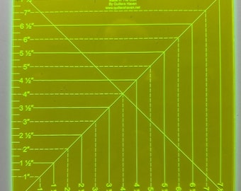May include: A square, transparent chart ruler with yellow grid lines and measurements in inches. The ruler has diagonal and horizontal lines, with measurements up to 7.5 inches. Text on the ruler reads "Made In The USA By Quilters Haven www.quiltershaven.net."