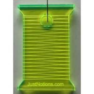 May include: A neon green acrylic quilting template in the shape of a thread spool. The template has etched lines representing thread and a small circular handle at the top. The text "JustNotions.com" is printed at the bottom.