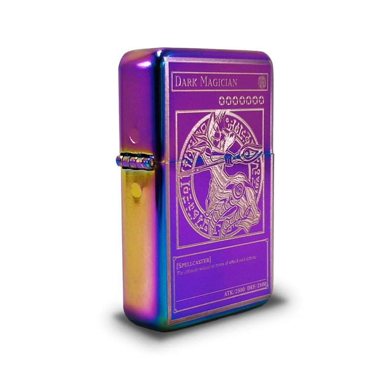 May include: A rainbow-colored metal lighter with an engraved image of the "Dark Magician" card from the Yu-Gi-Oh! Trading Card Game. The card features a dark wizard holding a staff and a circle of runes. The text on the card reads "DARK MAGICIAN" and "SPELLCASTER".