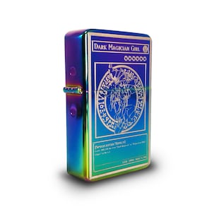 May include: A rainbow-colored metal lighter with an engraved image of the "Dark Magician Girl" card from the Yu-Gi-Oh! Trading Card Game. The card features a blue background with a circle of runes and a depiction of the character Dark Magician Girl. The card text reads "SPELLCASTER / EFFECT" and "ATK 2000 DEF 1700".