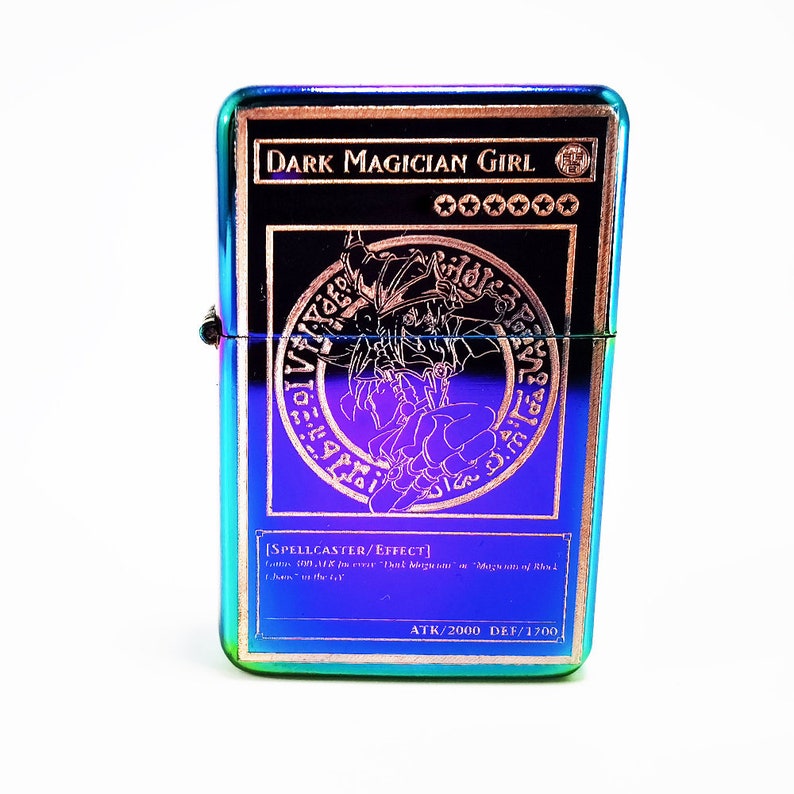 May include: A metallic lighter with a rainbow iridescent finish featuring a Dark Magician Girl Yu-Gi-Oh! card design. The card art shows the character in a purple circle with a gold border. The card text reads "DARK MAGICIAN GIRL" and "[SPELLCASTER/EFFECT]" with the attack and defense points listed as "ATK/2000 DEF/1700".