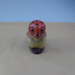 Könnte beinhalten: Ein Salz- und Pfefferstreuer aus Keramik in Form einer Eule mit roter, gelber und brauner Glasur. Die Eule hat einen runden Körper und einen kleinen Schnabel.