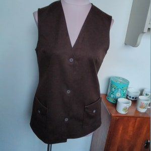 May include: A brown sleeveless vest with a V-neck, three buttons, and two pockets.