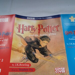 Peut inclure: Ensemble de trois livres audio de "Harry Potter et la Coupe de Feu" de J.K. Rowling, lus par Stephen Fry. Les couvertures sont rouges, jaunes et bleues, avec le titre dans une police stylisée et une illustration de Harry Potter sur un balai.
