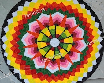 May include: A colorful circular rug with a mandala design. The rug is made of flowers and has a black border. The center of the rug is a sunburst design with a white circle in the center.