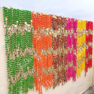 Puede incluir: Una guirnalda decorativa multicolor. Presenta hileras de cuentas verdes, naranjas, rosas, amarillas y rojas, intercaladas con detalles de espejo reflectantes. Ideal para ocasiones festivas, añade un toque de color y alegría.