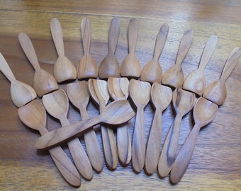 Könnte beinhalten: Ein Satz von 17 kleinen Holzlöffeln, die fächerförmig auf einer Holzoberfläche angeordnet sind. Die Löffel sind aus hellbraunem Holz gefertigt und haben eine abgerundete Schale und einen langen Stiel.