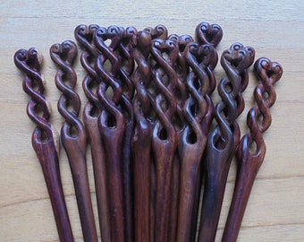 May include: A set of 14 wooden hair sticks with a twisted design and heart-shaped ends. The sticks are a dark reddish-brown color.