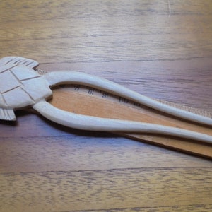 Puede incluir: Una horquilla para el pelo de madera con un dise&ntilde;o de tortuga tallada. La horquilla mide aproximadamente 15 cm de largo y est&aacute; hecha de madera clara.