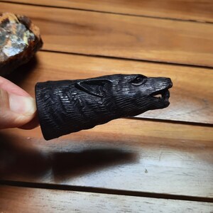 May include: A black wooden carving of an animal's head, possibly a wolf or dog, with detailed fur and facial features.