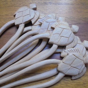 Puede incluir: Un juego de ocho palitos para el pelo de madera con dise&ntilde;os de tortugas talladas. Los palitos son de color marr&oacute;n claro y tienen un acabado liso.