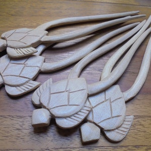 Puede incluir: Conjunto de seis palitos para el pelo de madera con tallas de cabeza de tortuga. Los palitos son de color marr&oacute;n claro y tienen un acabado liso. Las cabezas de tortuga son detalladas y tienen un color madera natural.