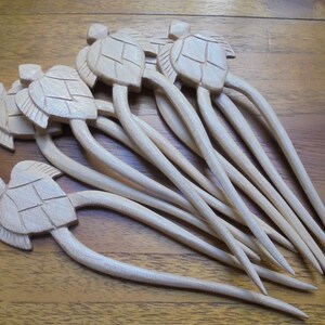 Puede incluir: Un conjunto de ocho palitos para el pelo de madera con tapas en forma de tortuga. Los palitos son de color marr&oacute;n claro y tienen un acabado liso. Las tapas de tortuga est&aacute;n talladas con detalle y tienen un color madera natural.
