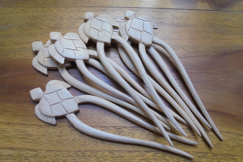 Puede incluir: Un conjunto de ocho palitos para el pelo de madera con tapas en forma de tortuga. Los palitos son de color marr&oacute;n claro y tienen un acabado liso. Las tapas de tortuga est&aacute;n talladas con detalle y tienen un color madera natural.