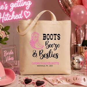 May include: A beige canvas tote bag featuring a pink cowboy boot graphic and black text that reads Boots Booze & Besties, with additional pink text stating Caressa's Bachelorette and Nashville, TN - 2025 printed on the front surface.