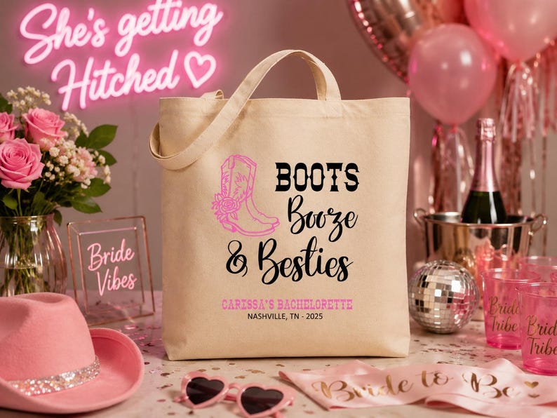 May include: A beige canvas tote bag featuring a pink cowboy boot graphic and black text that reads Boots Booze & Besties, with additional pink text stating Caressa's Bachelorette and Nashville, TN - 2025 printed on the front surface.