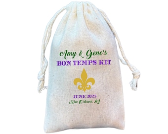 May include: A white drawstring bag with the text "Amy & Gene's BON TEMPS KIT" in green and purple lettering. A gold fleur-de-lis is printed below the text. The date "JUNE 2025" and the location "New Orleans, La" are printed in green below the fleur-de-lis.