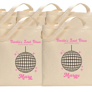 May include: Six white canvas tote bags with pink text and a black disco ball graphic. The text on the bags reads "Darla's Last Disco Scottsdale 2025" and includes the names "Mary" and "Margo".